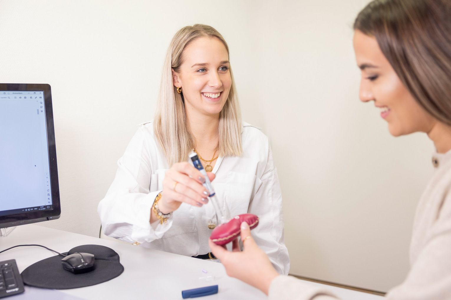 Beratungsgespräch in Praxiszimmer zwischen Ärztin und Patientin über Insulinspritze