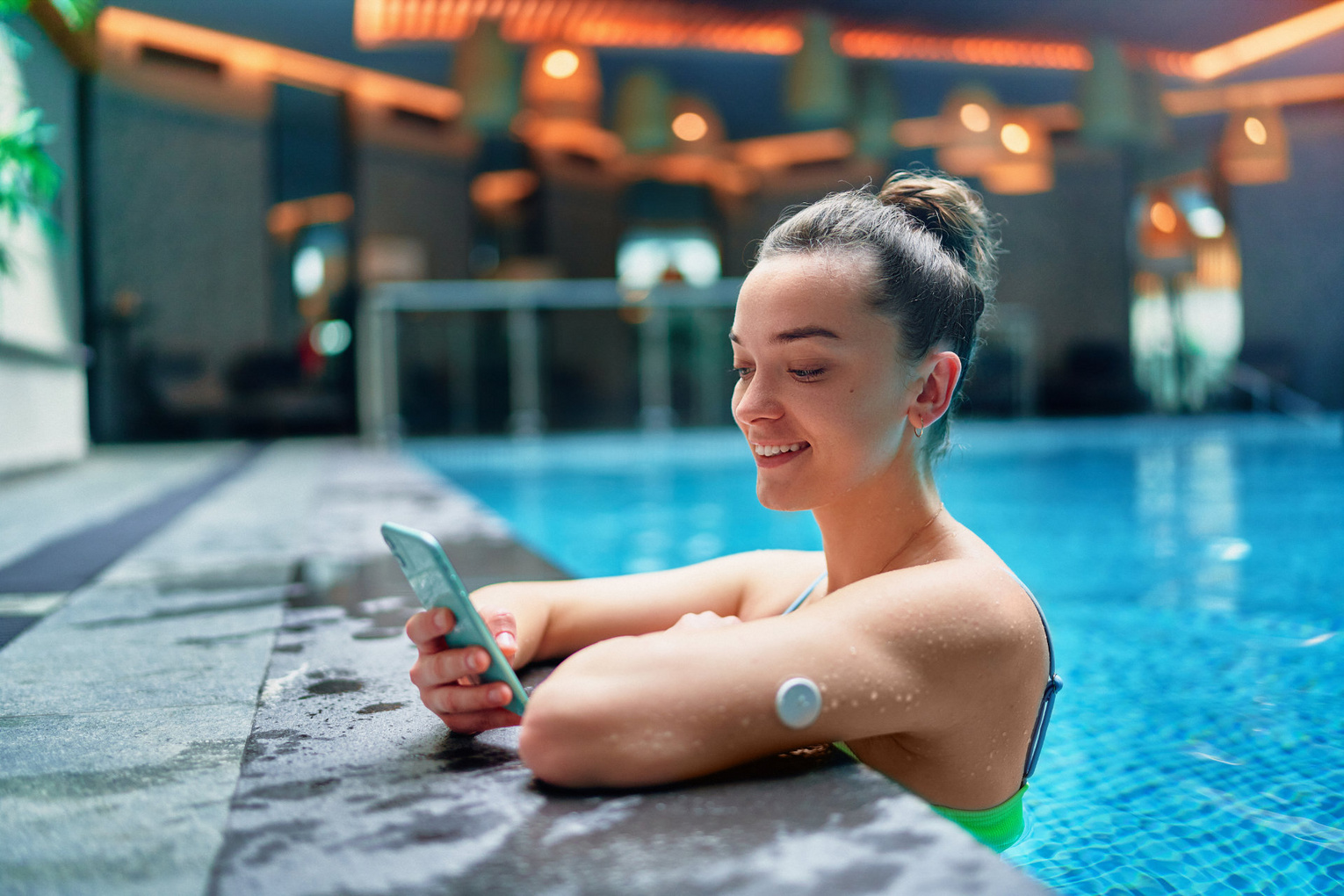 Eine Diabetes Patientin mit CGM Messgerät in einem Schwimmbecken